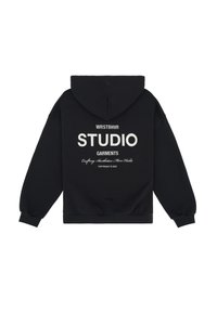 Černá mikina s kapucí a volným střihem, s bílým potiskem na zádech: "WRSTBHVR STUDIO GARMENTS" a dalšími detaily.