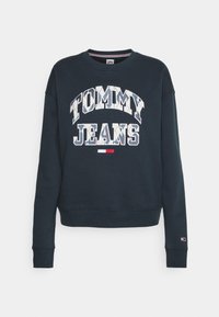 Sudadera azul marino con cuello redondo, que presenta "TOMMY JEANS" en texto blanco y multicolor. Puños y dobladillo acanalados, con etiqueta del logo en la manga.