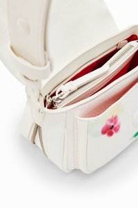 Borsa a mano bianca in pelle con interno rosso, caratterizzata da un design floreale sulla parte anteriore, doppi zip e una tracolla regolabile.