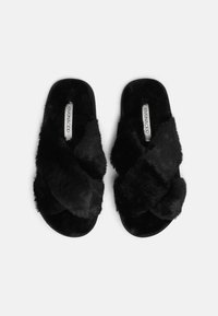 Pantofole nere in pelliccia sintetica con design a fascia incrociata, suola piatta e texture morbida. Etichetta del marchio visibile sulla soletta. Adatte per uso interno.