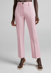 Rosa skräddarsydda byxor med raka ben, tillverkade av ett mjukt tyg. Har en frontknapp, två sidofickor och rena sömmar.