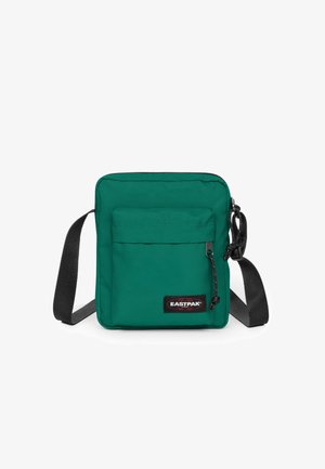 Grüne Nylon Umhängetasche mit einem Reißverschluss-Hauptfach, einer Fronttasche, einem verstellbaren schwarzen Tragegurt und einem Markenlogo-Patch.