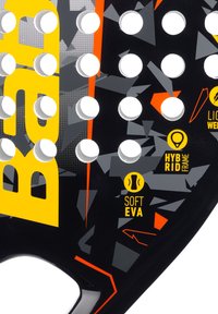 Zwarte padel racket met een gestructureerd oppervlak, meerdere ronde gaten, gedurfde gele branding en details zoals "Soft EVA" en "Hybrid Frame."