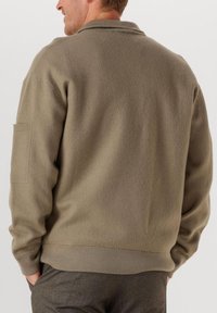 Fleece-Sweatshirt in Olivgrün mit Kragen und gerippten Bündchen. Verfügt über eine Seitentasche und eine weiche, strukturierte Oberfläche.