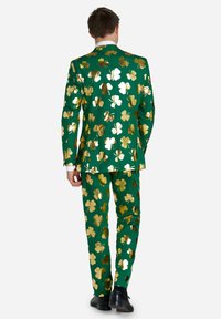 Zelena obleka z zlatim šamrock vzorcem, s prilagojenim dizajnom, usklajenimi hlačami in gladko teksturo. Primerna za praznične priložnosti.