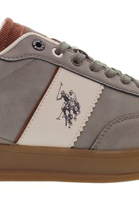 Šedé semišové tenisky s hnědou podrážkou, béžovým panelem s dvěma hráči póla na koních a šedými tkaničkami.