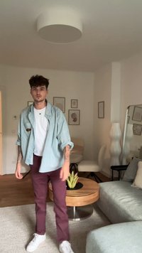 Pessoa a usar uma camisa oversized riscada em azul claro, t-shirt branca e calças bordô, com sapatilhas brancas e braços tatuados.