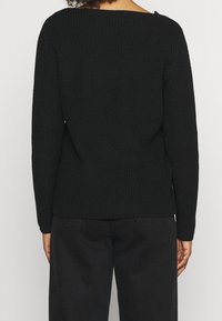 Schwarzer gerippter Pullover mit weitem Halsausschnitt und langen Ärmeln, der ein strukturiertes Strickmuster aufweist. Keine sichtbaren Beschläge oder Akzente.
