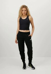 Must teeb ja spordipüksid, mis on valmistatud hingavast kangast, omavad vormitud lõiget ja peent brändi logo, koos mustade spordijalatsitega.