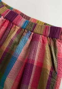 Elastische tailleband met meerkleurige verticale en horizontale strepen op gestructureerde stof, met een zak aan de rechterkant.