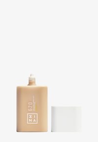 Flacon de fond de teint liquide beige avec un capuchon cylindrique blanc. Surface texturée avec une étiquette en relief et des repères de mesure. Taille : 30 ml.