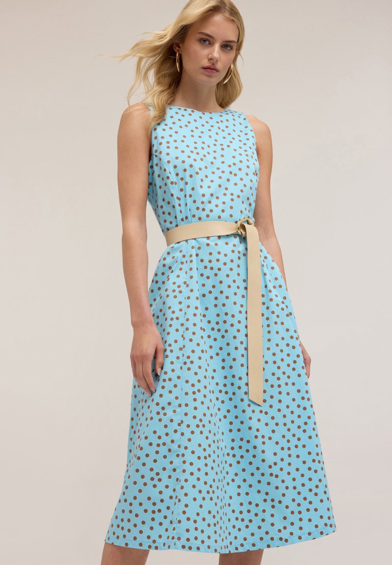 Rochie fără mâneci, de culoare albastru deschis, cu buline maro, siluetă A-line, talie strânsă cu un brâu crem, până la genunchi, din material de bumbac.