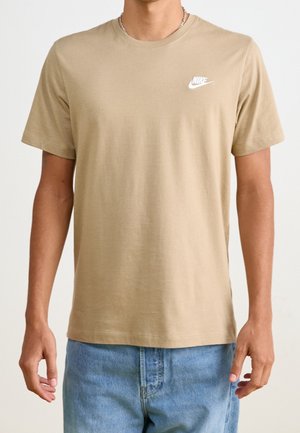 Beige bomulds T-shirt med korte ærmer, prydet med et hvidt Nike-logo på venstre brystområde. Enkel rund halsudskæring og afslappet pasform.
