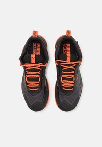 Mustad must shoes musta ja oranži aktsentidega, millel on võrknahast ülemine osa, tekstuurilised detailid, silmapaistvad paelad ja logo keele ning kanna peal.