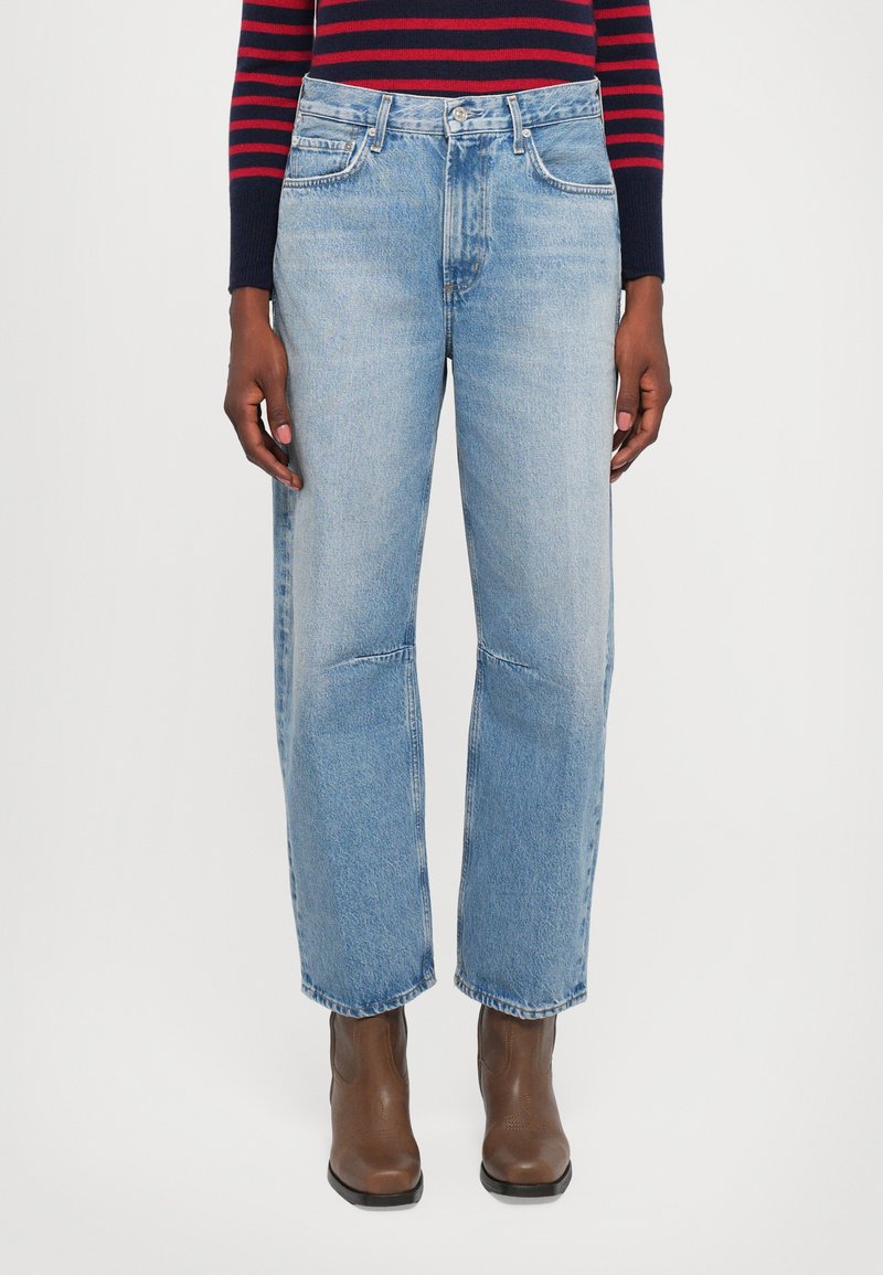 Light blue denim jeans with a straight leg design, featuring front pockets, belt loops, and visible stitching details. Worn with brown ankle boots.