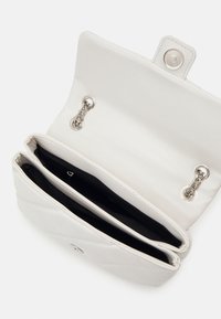 Bílá kožená peněženka se dvěma přihrádkami, stříbrnými kovovými prvky, západkou na cvok a texturovaným povrchem. Vnitřek je podšitý černou tkaninou.