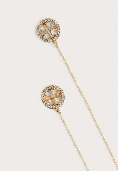 Χρυσά σκουλαρίκια με κυκλικά κρεμαστά στοιχεία διακοσμημένα με διάφανα κρύσταλλα και σχέδιο με κοψίματα, κρεμασμένα από λεπτές αλυσίδες.