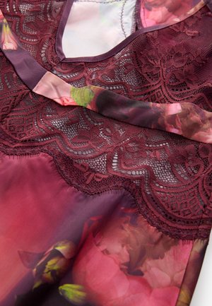 Bordeauxrode top met bloemenprint, voorzien van kanten accenten, een gladde zijden textuur, een V-halslijn en delicate bloemenpatronen in tinten roze en groen.