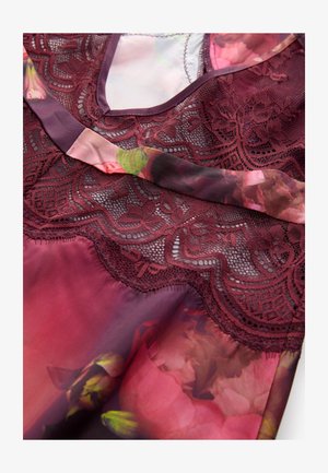 Vínový top s květinovým potiskem zdobený krajkovými detaily, hladkou hedvábnou texturou, výstřihem do V a jemnými květinovými vzory v odstínech růžové a zelené.