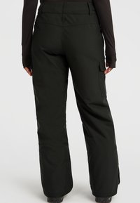 Zwarte sneeuwbroek met een losse pasvorm, voorzien van zijvakjes en versterkt materiaal aan de cuffs voor duurzaamheid. Soepele textuur en minimalistisch design.