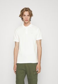 Hvid bomulds polo shirt med kort krave, to-knap lukning og 'GAP' logo i lys syning; parret med olivengrønne cargo shorts.