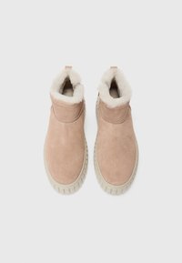 Bottines en daim rose avec une doublure blanche pelucheuse et une semelle en caoutchouc texturée. Comprend une languette et des détails de couture minimalistes.