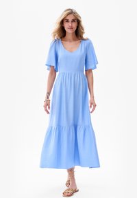 Jasnoniebieska sukienka do kolan z dekoltem w kształcie litery V, z rozkloszowanymi krótkimi rękawami i warstwowym krojem. Wykonana z gładkiego, teksturowanego materiału.