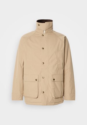 Beige jas met een hoge kraag, ritssluiting en drukknoopjes. Voorzien van twee voorkruiken en een gestructureerde stof. Geschikt voor casual wear.