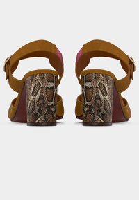 Καφέ σουέντ πέδιλα με τακούνι και ροζ λεπτομέρεια, με τακούνι τύπου μπλοκ με σχέδιο φίδι και λουράκι με αγκράφα για σταθερή εφαρμογή.