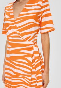 Oranges Kleid mit einem Zebra-Streifenmuster in Weiß, mit einem V-Ausschnitt, kurzen Ärmeln und einer gewickelten Taillendetail. Weicher, strukturierter Stoff.