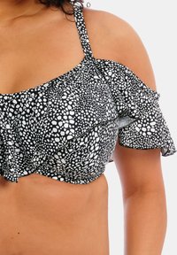 Haut de bikini à pois noir et blanc avec des manches froncées et un design épaules dénudées. Tissu doux avec une texture lisse.