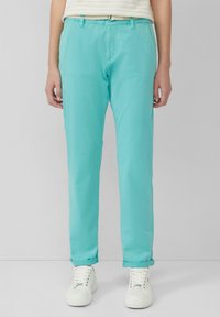 Turquoise katoenen broeken met een relaxte pasvorm, voorzien van opgerolde uiteinden en riemlussen. Gecombineerd met witte sneakers voor een complete look.