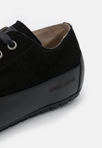 Czarne zamszowe buty z gumową podeszwą i logo. Posiadają metalowe oczka i czarne sznurowadła, z gładką skórzaną akcentą na pięcie.