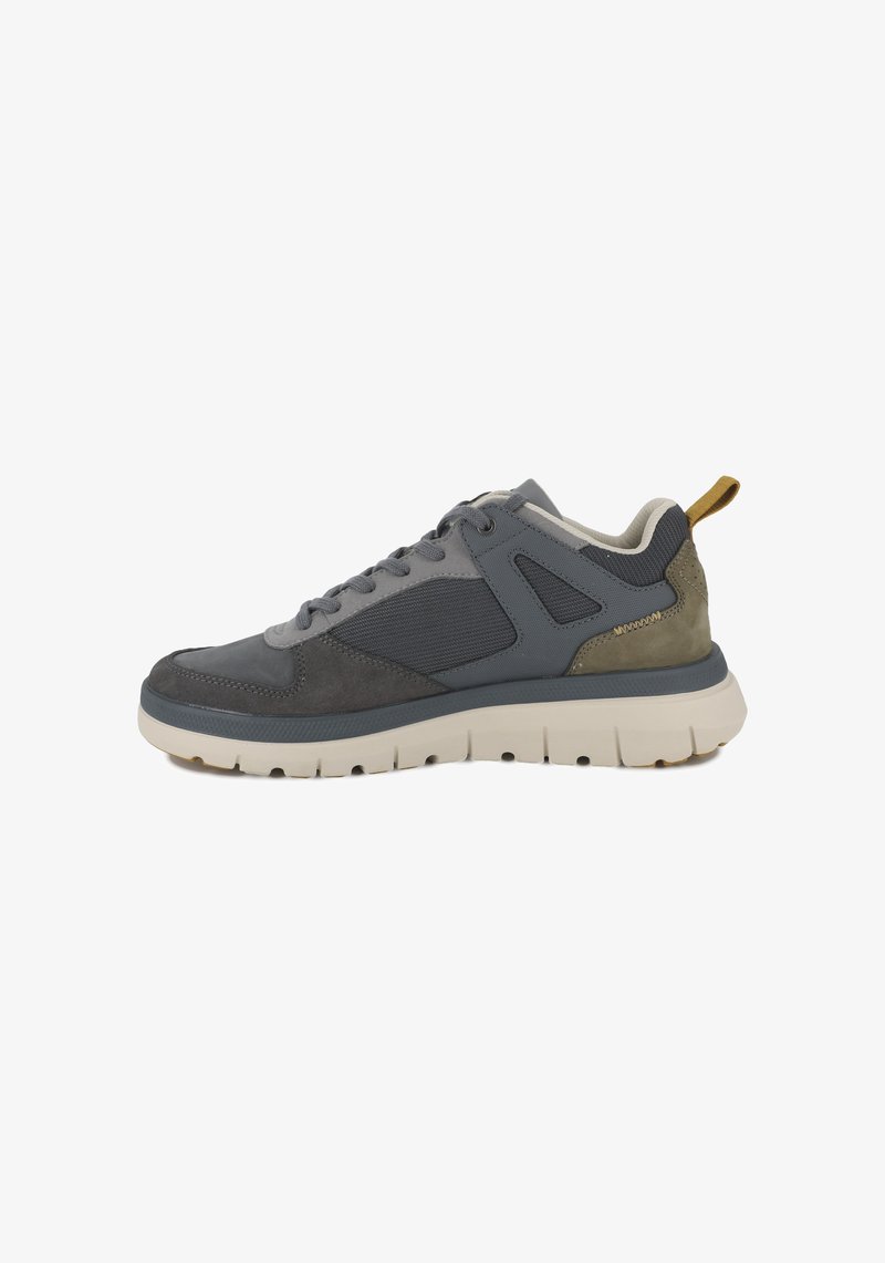Chaussure de sport grise avec un mélange de matériaux lisses et texturés, panneaux en maille, semelle en caoutchouc et une touche marron sur la languette du talon.