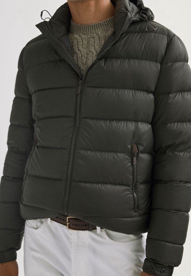 Steppjacke in Dunkelgrün, mit durchgehendem Reißverschluss und Kapuze. Verfügt über horizontal gesteppten Stoff, zwei seitliche Reißverschlusstaschen und elastische Bündchen.