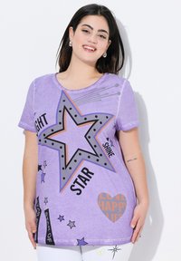 Camiseta de manga corta morada con un gran gráfico de estrella que incluye texto, puntos y corazones. Tejido suave y texturizado con un corte holgado.