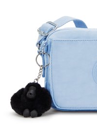 Borsa di stoffa azzurro chiaro con forma rettangolare e hardware argentato. Presenta un portachiavi a forma di gorilla peloso nero come dettaglio decorativo.