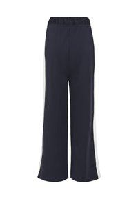 Pantalons larges bleu marine avec taille élastique et rayures blanches sur les côtés, vus de dos sur un fond blanc.