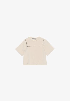 Crème kortemouwen t-shirt gemaakt van een zachte stof, heeft een horizontale lijn van kleine studaccenten over de borst en een relaxte pasvorm.