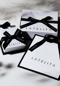 Three white gift boxes with black ribbon: one larger box with "LATELITA" printed on the front and two smaller, similarly designed boxes.