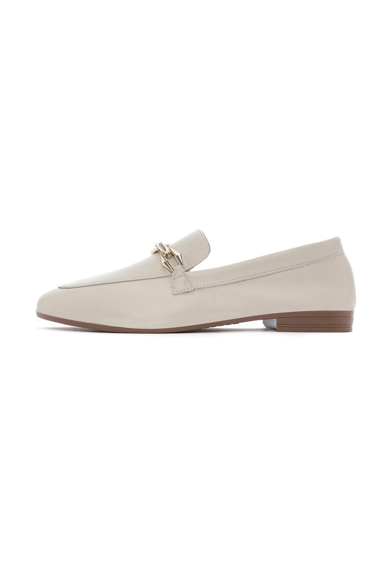 Mocassini in pelle beige con tacco piatto, caratterizzati da una fibbia decorativa in oro sulla tomaia e un design minimale. Texture liscia e forma snella.