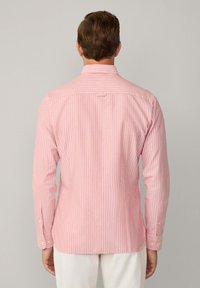 Camicia a maniche lunghe di colore rosa chiaro con strisce verticali bianche, dotata di colletto normale, polsini abbottonati e vestibilità sagomata.