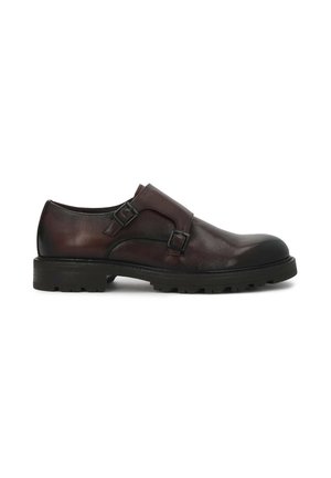 Mørkebrune læder monk strap sko med dobbelt spænde og tyk sort gummisål med dybe riller, sidevisning på hvid baggrund.