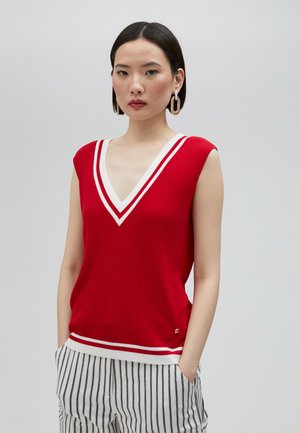Top sin mangas de rayas rojas y con escote en V, con rayas blancas a lo largo del escote y el dobladillo, combinado con pantalones a rayas. Detalles en dorado presentes.