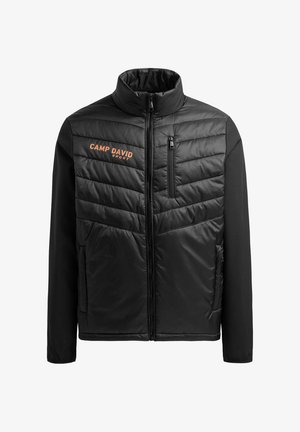 Zwarte jas met gewatteerde voorkant, hoge kraag en oranje "CAMP DAVID" logo. Heeft een ritssluiting op de borst en zachte stoffen mouwen.