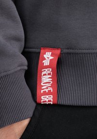 Sivá mikina so zúženými manžetami, ktorá má červenú nášivku s textom "ODSTRÁŇTE PIVO". Hladká textúra a priliehavý strih so bočnými švami.