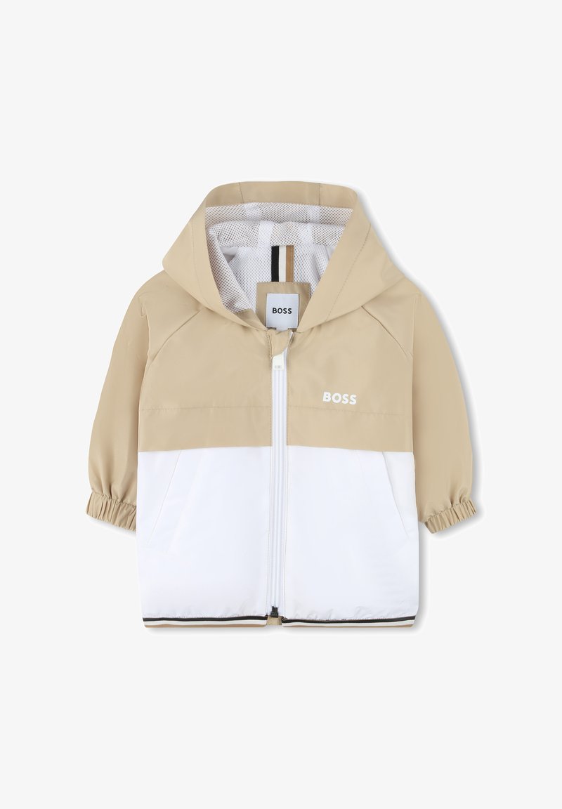 Šviesiai rudos ir baltos spalvos lengva striukė su gobtuvu, elastingomis rankogaliais, priekiniais užtrauktukais ir subtiliu ženklinimu. Lygus paviršius su spalvų blokavimo dizainu.