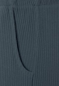 Dunkelgrauer gerippter Stoff bietet eine glatte Textur mit einer seitlichen Tasche, die durch eine Naht hervorgehoben wird und das Design sowie die Funktionalität des Kleidungsstücks unterstreicht.