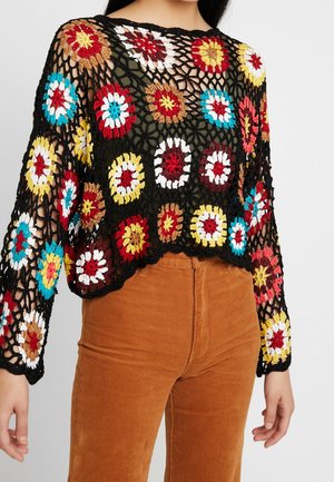 Zwarte gehaakte top met lange mouwen en meerkleurige bloemenpatronen, gedragen over een groen hemd, gecombineerd met hooggetailleerde bruine corduroy broek.