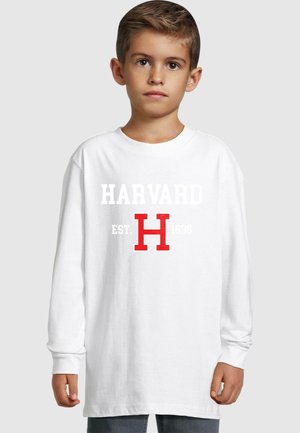Fehér, hosszú ujjú póló, melynek elején vastag fehér betűkkel szerepel a "HARVARD" felirat egy nagy piros "H" fölött, és a "EST. 1636" szürke színben. Könnyű anyag.